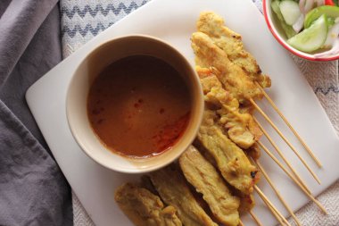 Fıstık ve salatalık soslu, beyaz bir tabakta servis edilen domuz eti..