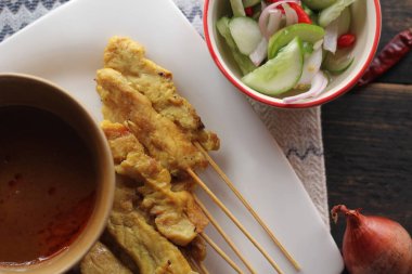 Fıstık ve salatalık soslu, beyaz bir tabakta servis edilen domuz eti..