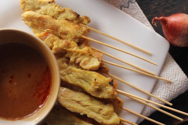 Fıstık ve salatalık soslu, beyaz bir tabakta servis edilen domuz eti..