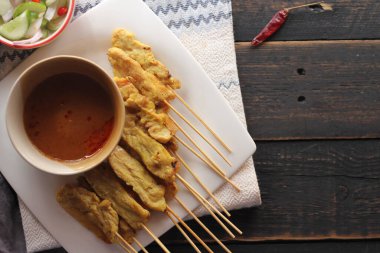Fıstık ve salatalık soslu, beyaz bir tabakta servis edilen domuz eti..