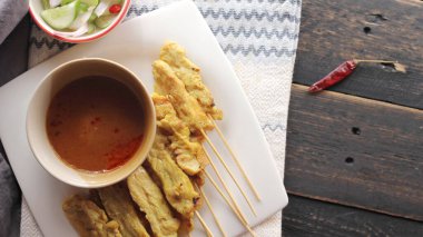 Fıstık ve salatalık soslu, beyaz bir tabakta servis edilen domuz eti..