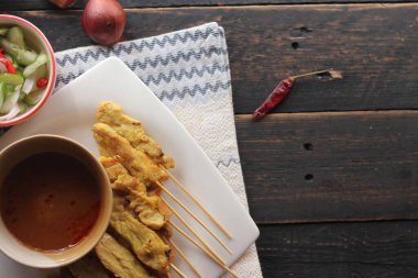 Fıstık ve salatalık soslu, beyaz bir tabakta servis edilen domuz eti..