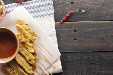 Fıstık ve salatalık soslu, beyaz bir tabakta servis edilen domuz eti..