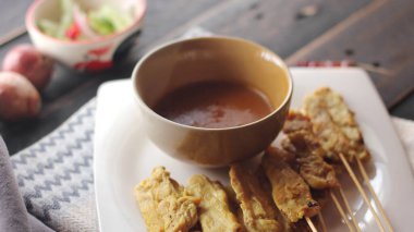 Fıstık ve salatalık soslu, beyaz bir tabakta servis edilen domuz eti..