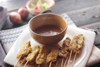 Fıstık ve salatalık soslu, beyaz bir tabakta servis edilen domuz eti..