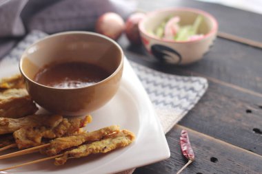 Fıstık ve salatalık soslu, beyaz bir tabakta servis edilen domuz eti..