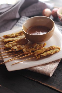 Fıstık ve salatalık soslu, beyaz bir tabakta servis edilen domuz eti..