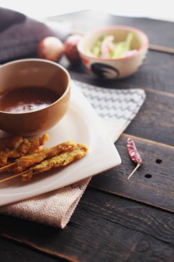 Fıstık ve salatalık soslu, beyaz bir tabakta servis edilen domuz eti..