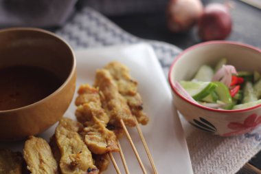 Fıstık ve salatalık soslu, beyaz bir tabakta servis edilen domuz eti..