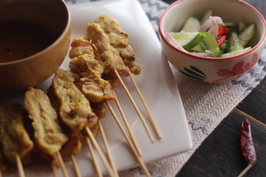 Fıstık ve salatalık soslu, beyaz bir tabakta servis edilen domuz eti..