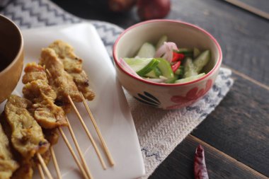 Fıstık ve salatalık soslu, beyaz bir tabakta servis edilen domuz eti..