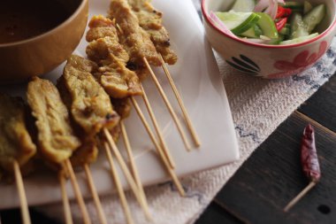 Fıstık ve salatalık soslu, beyaz bir tabakta servis edilen domuz eti..