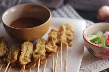 Fıstık ve salatalık soslu, beyaz bir tabakta servis edilen domuz eti..