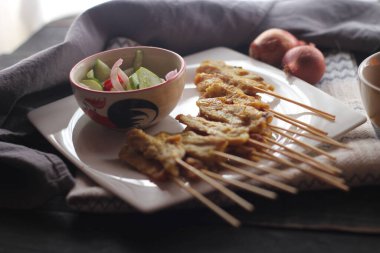 Fıstık ve salatalık soslu, beyaz bir tabakta servis edilen domuz eti..