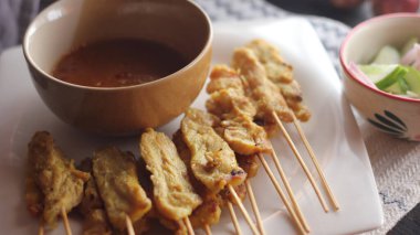 Fıstık ve salatalık soslu, beyaz bir tabakta servis edilen domuz eti..