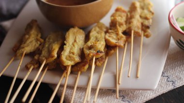 Fıstık ve salatalık soslu, beyaz bir tabakta servis edilen domuz eti..