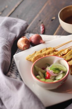 Fıstık ve salatalık soslu, beyaz bir tabakta servis edilen domuz eti..