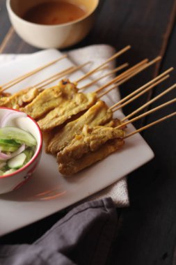 Fıstık ve salatalık soslu, beyaz bir tabakta servis edilen domuz eti..