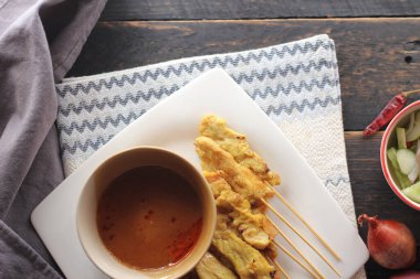 Fıstık ve salatalık soslu, beyaz bir tabakta servis edilen domuz eti..