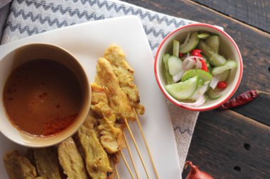 Fıstık ve salatalık soslu, beyaz bir tabakta servis edilen domuz eti..