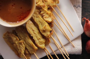 Fıstık ve salatalık soslu, beyaz bir tabakta servis edilen domuz eti..