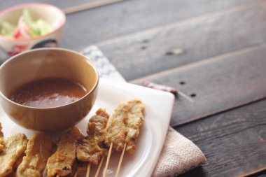 Fıstık ve salatalık soslu, beyaz bir tabakta servis edilen domuz eti..