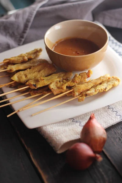Fıstık ve salatalık soslu, beyaz bir tabakta servis edilen domuz eti..