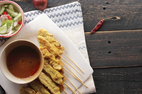 Fıstık ve salatalık soslu, beyaz bir tabakta servis edilen domuz eti..