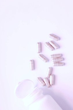 Gri hap kapsülleri ve ilaç şişeleri beyaz bir masaya yerleştirildi..