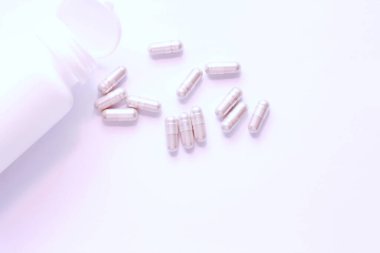 Gri hap kapsülleri ve ilaç şişeleri beyaz bir masaya yerleştirildi..