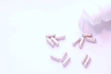 Gri hap kapsülleri ve ilaç şişeleri beyaz bir masaya yerleştirildi..