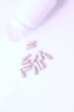 Gri hap kapsülleri ve ilaç şişeleri beyaz bir masaya yerleştirildi..