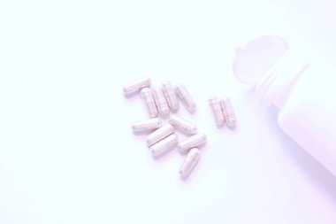 Gri hap kapsülleri ve ilaç şişeleri beyaz bir masaya yerleştirildi..