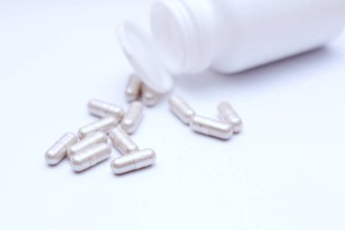 Gri hap kapsülleri ve ilaç şişeleri beyaz bir masaya yerleştirildi..