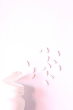 Beyaz haplar ve ilaç şişeleri beyaz bir masaya konuldu..