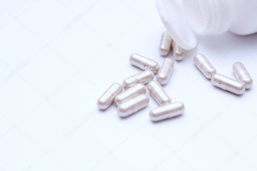 Gray pill capsules and pill bottles were placed on a white table.