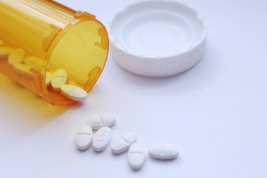 Oval haplar ve turuncu hap şişeleri beyaz masanın üstüne serilmişti..