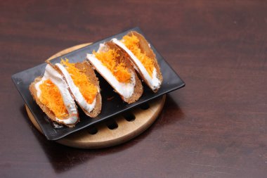 Tayland yemeği, Tayland Çıtır Krepleri, kahverengi ahşap bir masada siyah tabakta servis edilir..