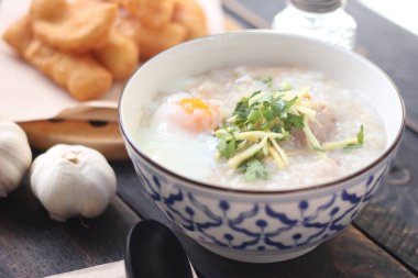 Tayland desenli bir bardakta pirinç lapası ve Asya usulü bir bardakta, siyah bir masada, 