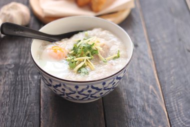 Tayland desenli bir bardakta pirinç lapası ve Asya usulü bir bardakta, siyah bir masada, 