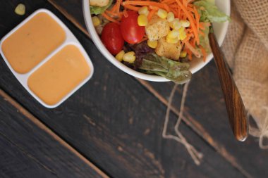 Sezar salatası ve Sezar sosu. Siyah ahşap bir masada.