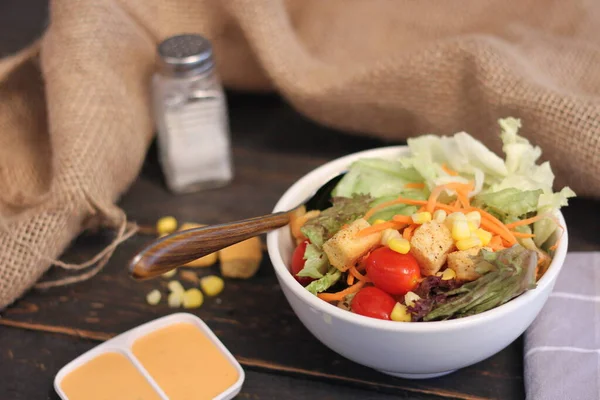 Sezar salatası ve Sezar sosu. Siyah ahşap bir masada.