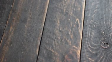 A man's hand is stroking on a black wooden plank.