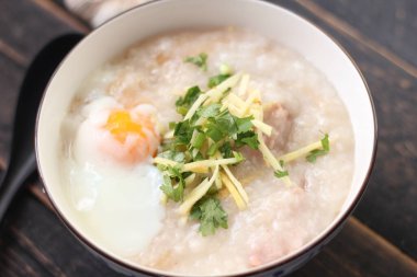 Siyah ahşap bir masada servis edilen Tayland usulü bir fincanda şaka ya da congee. Asya kahvaltısı..