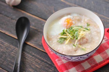 Siyah ahşap bir masada servis edilen Tayland usulü bir fincanda şaka ya da congee. Asya kahvaltısı..