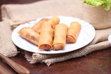 Kızarmış börek, sebze ve domatesle birlikte beyaz ahşap bir masada siyah bir tabağa konur ve sosu sosa batırır..