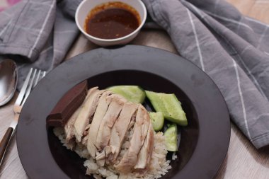 Ahşap bir masada sosla servis edilen Çin tavuğu pilavı..