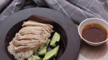 Ahşap bir masada sosla servis edilen Çin tavuğu pilavı..