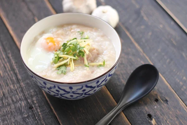 Siyah ahşap bir masada servis edilen Tayland usulü bir fincanda şaka ya da congee. Asya kahvaltısı..