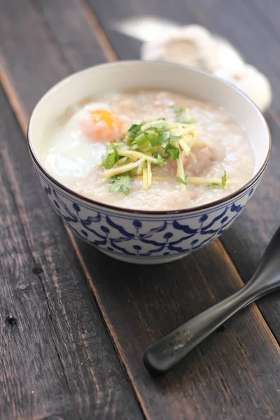 Siyah ahşap bir masada servis edilen Tayland usulü bir fincanda şaka ya da congee. Asya kahvaltısı..